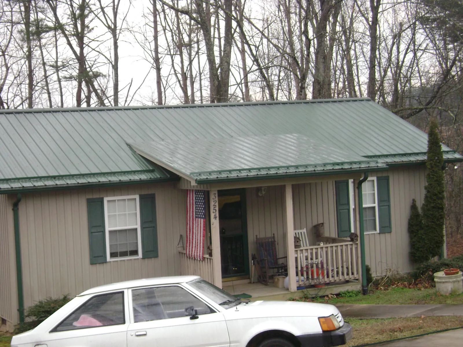 Green metal roof and front porch on a tan sided cottage in Newberry
