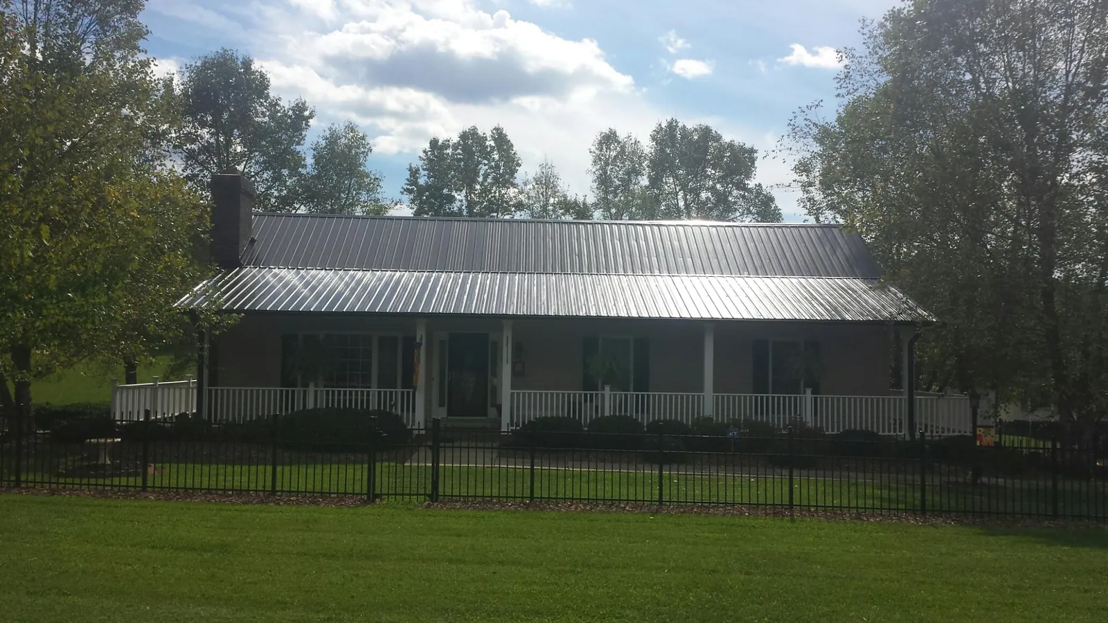 Gray metal roof on a brick ranch with a full width front porch — Gutter Guard Installation work by our crew in Newberry
